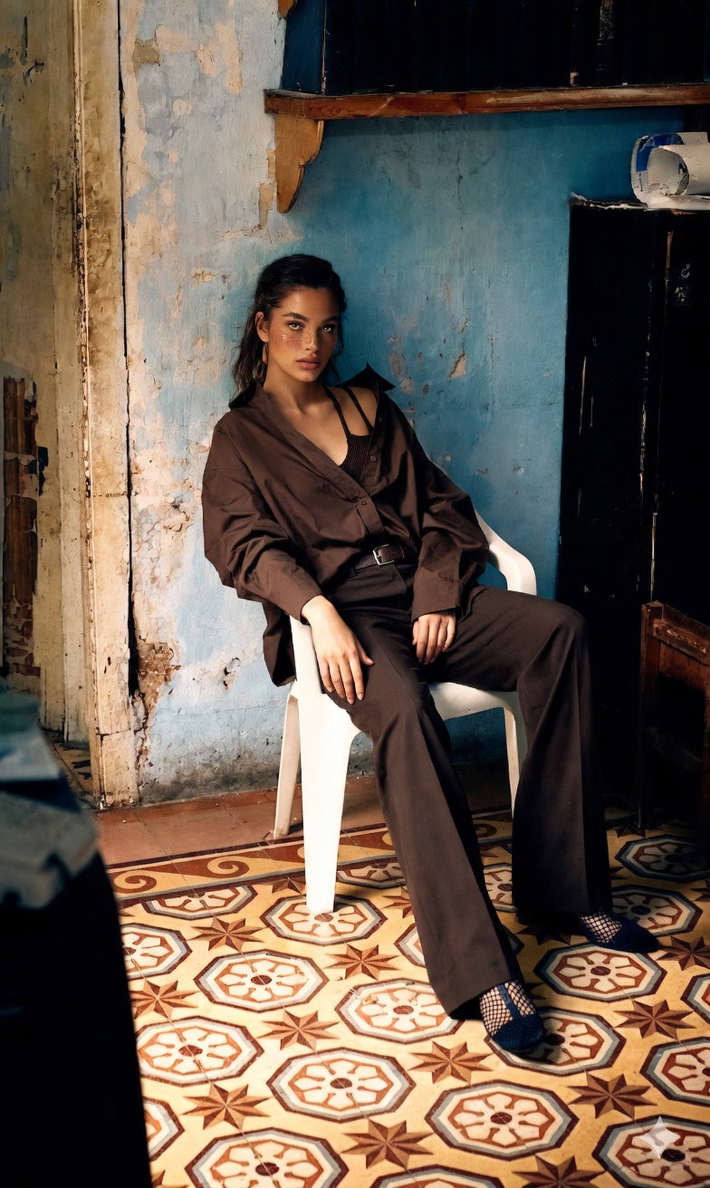 Woman sitting on a chair in a room with blue walls and patterned floor wearing Adeptt clothing.